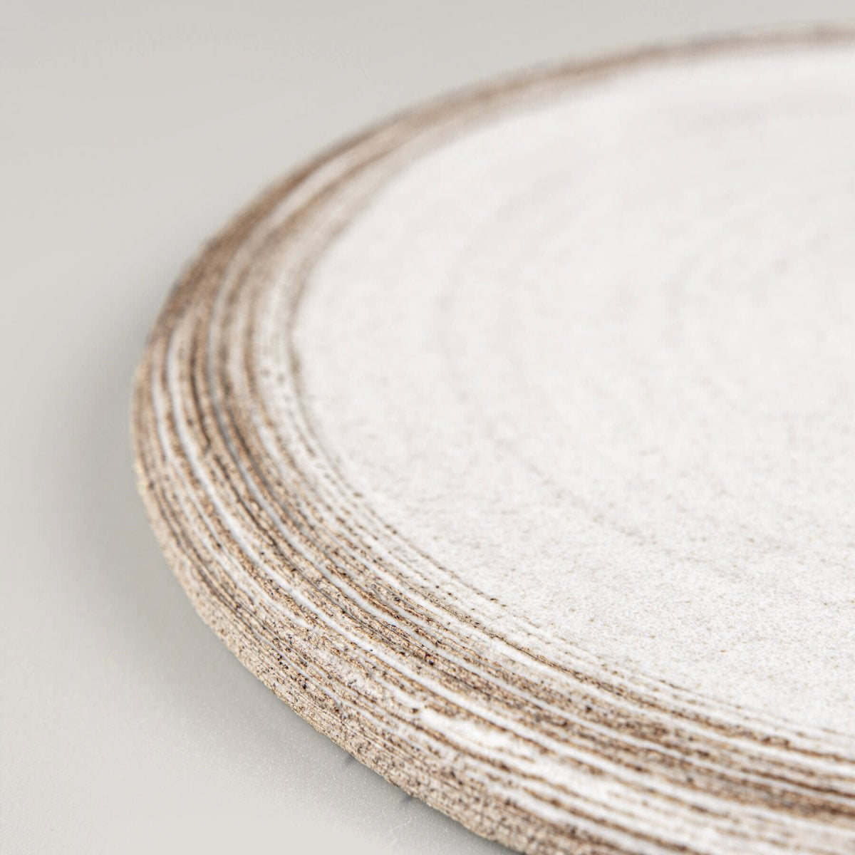 Detail of textured rim on artisan-made ceramic plate in matte white.