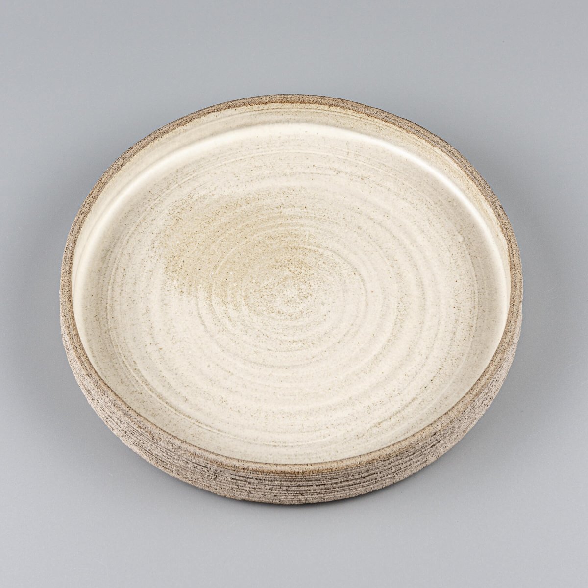 Elegant stoneware dinner plate with matte white glazed interior and textured carved exterior.