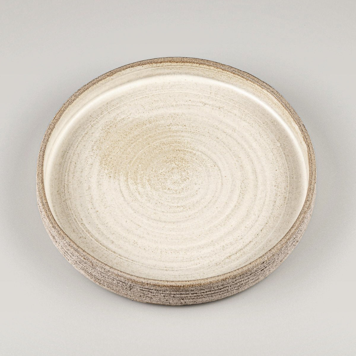 Elegant stoneware dinner plate with matte white glazed interior and textured carved exterior.