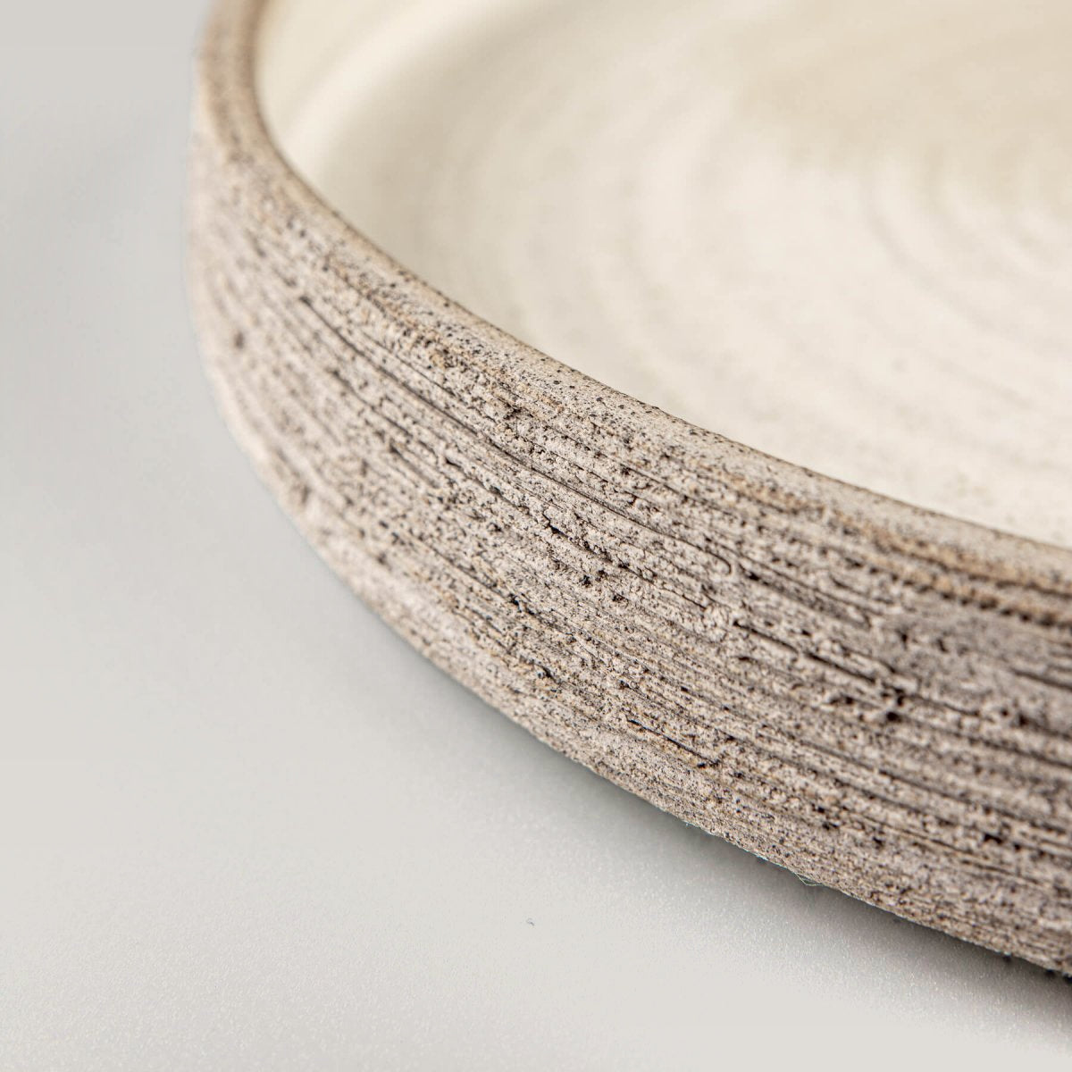 Close-up of hand-carved stoneware plate showing raw clay texture.