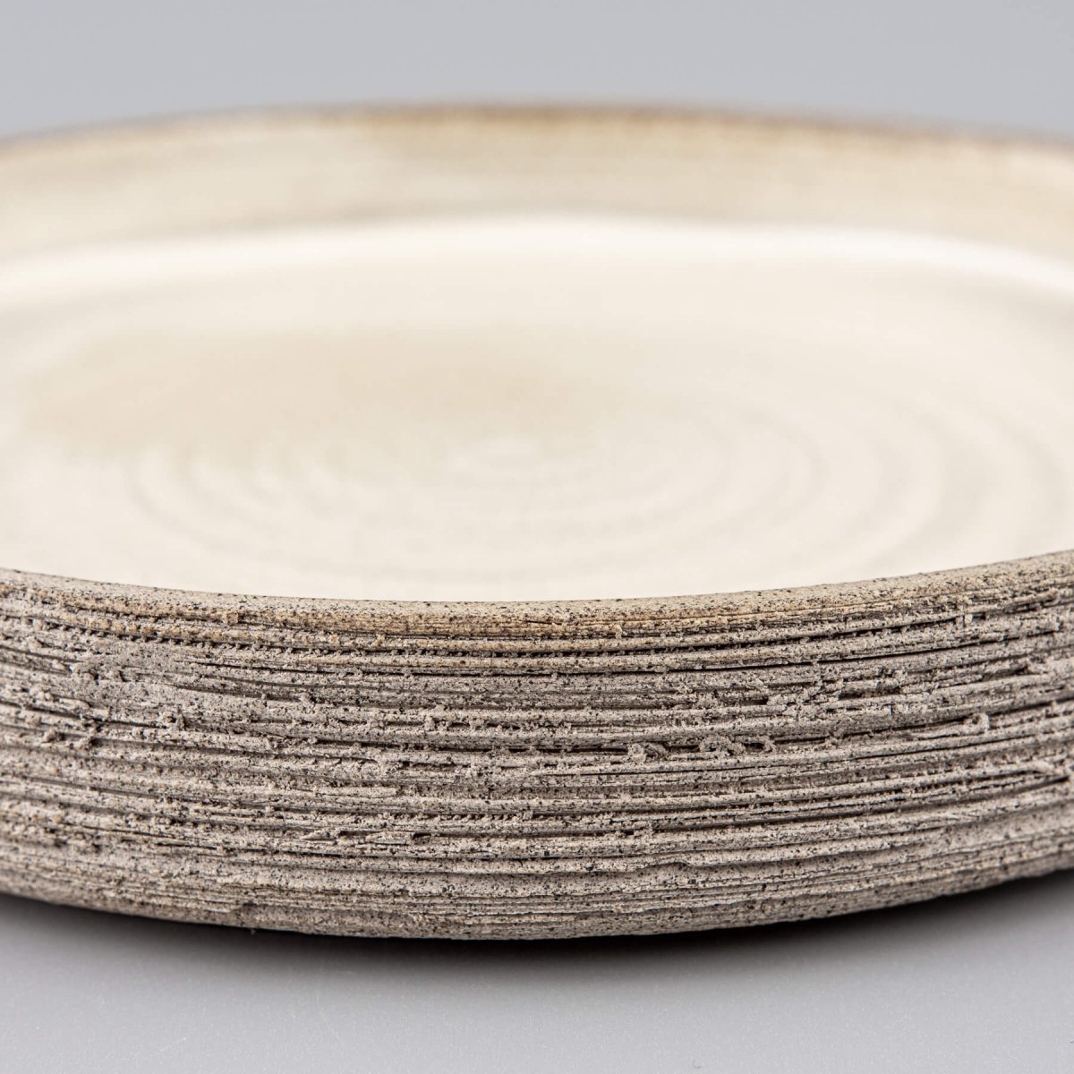 Side view of artisanal stoneware plate with straight edges and carved details.