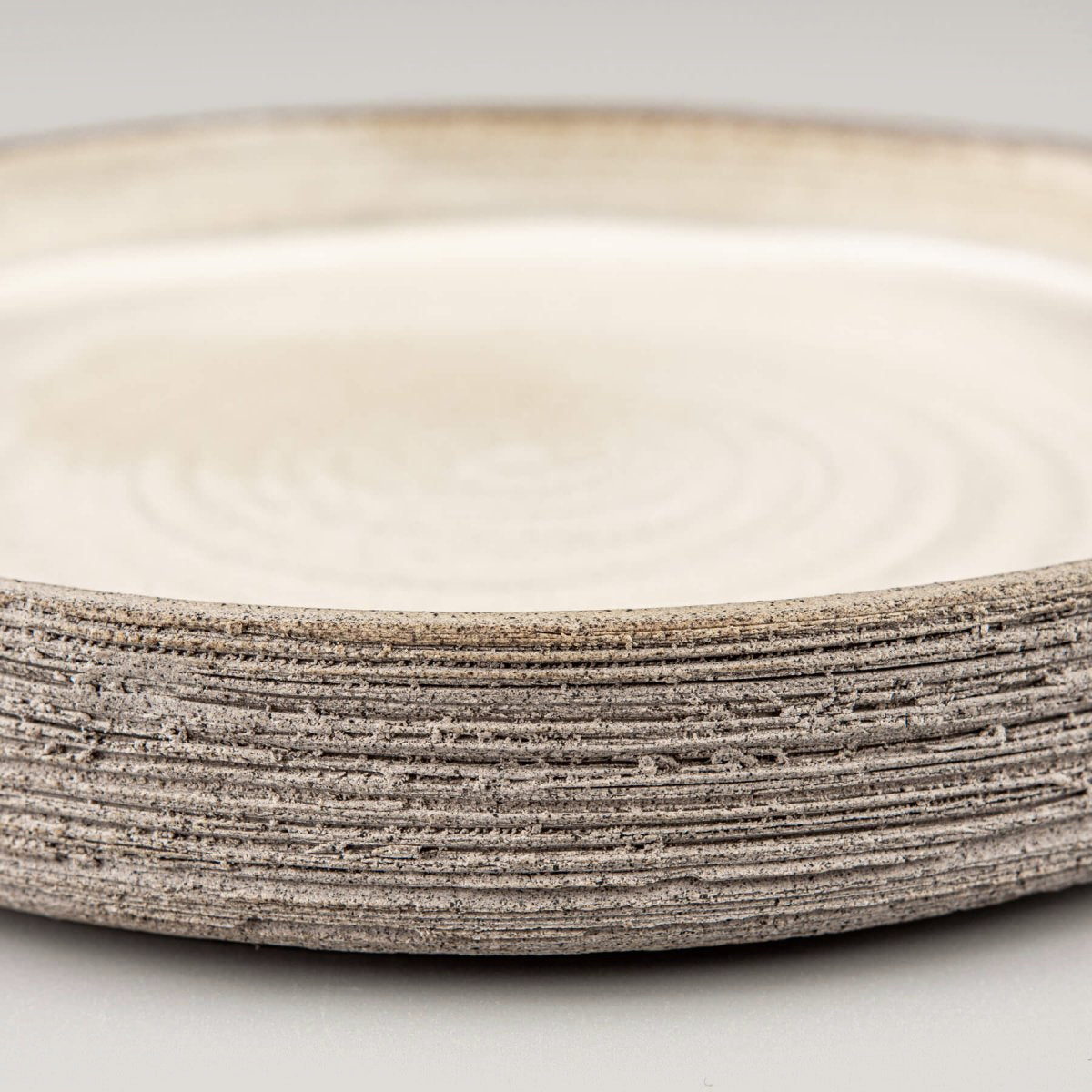 Side view of artisanal stoneware plate with straight edges and carved details.