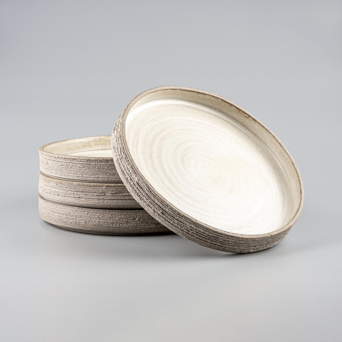 Stacked handmade dinner plates with matte glaze and raw exterior.