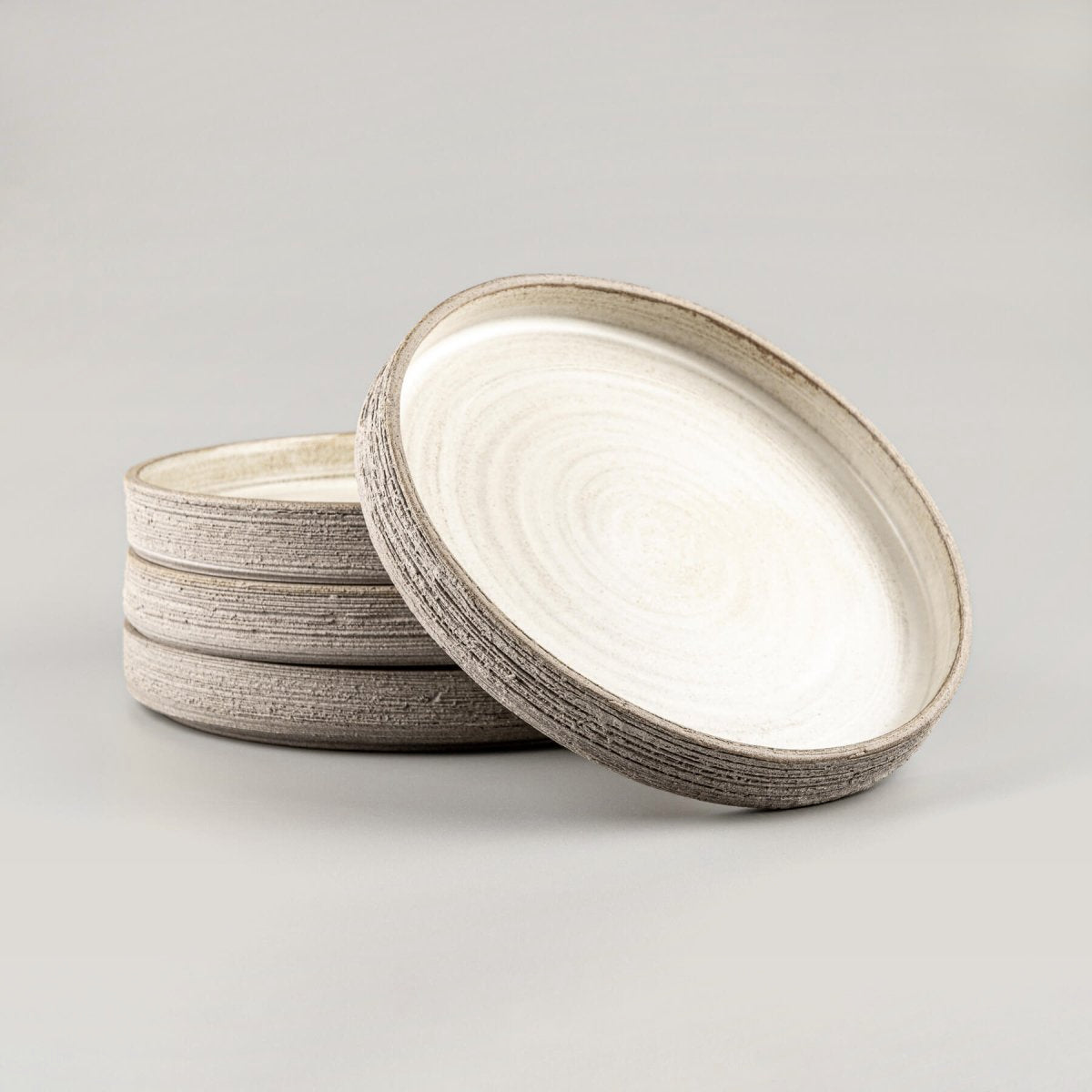 Stacked handmade dinner plates with matte glaze and raw exterior.