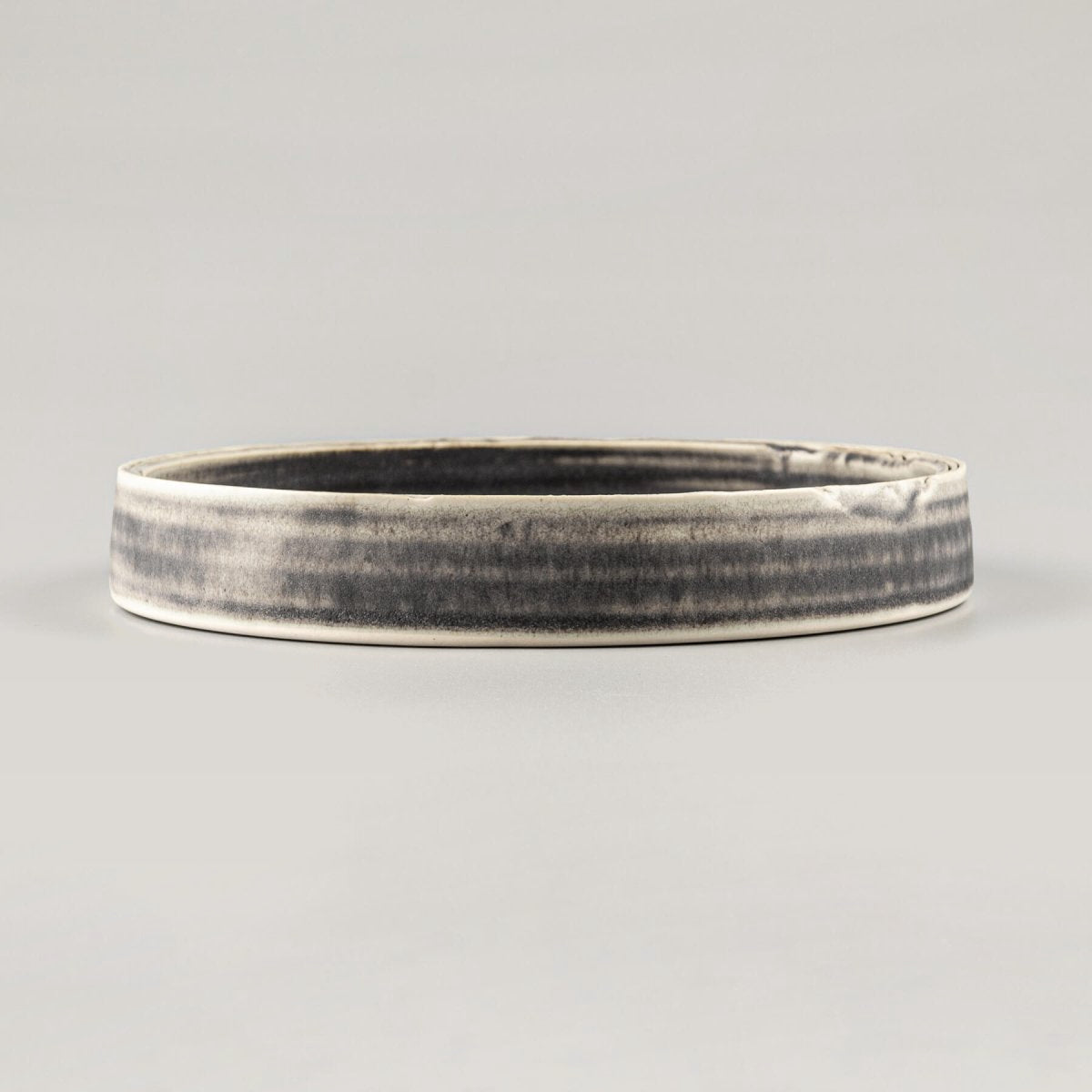 Side profile of artisanal handmade plate with modern straight-sided design for Michelin-star chefs.