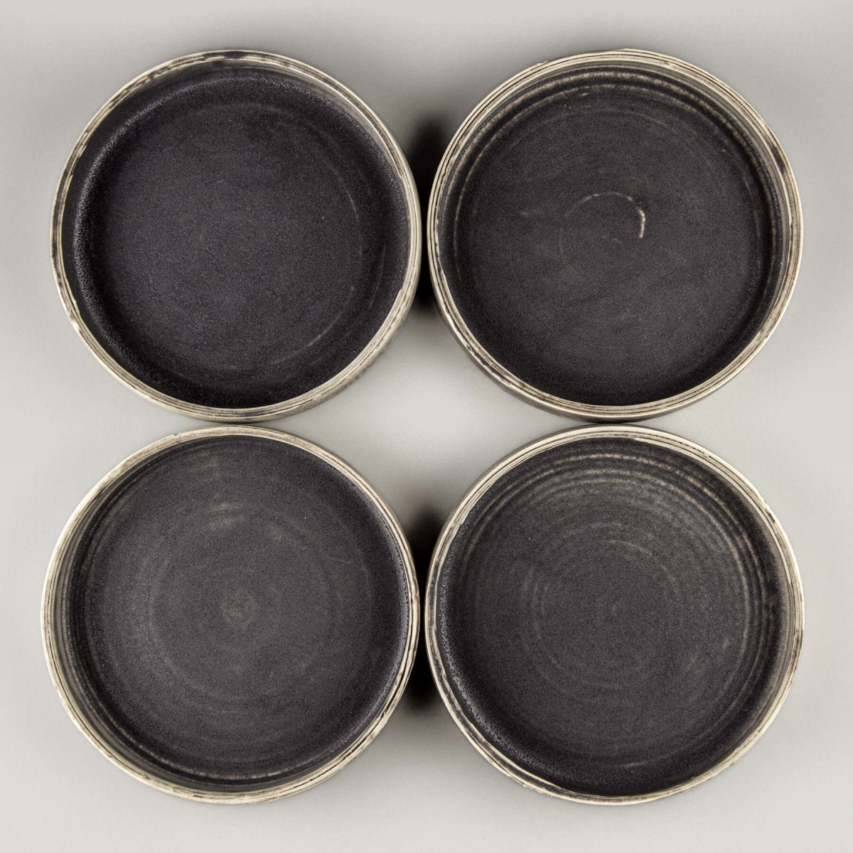 Overhead view of four handmade ceramic plates arranged for fine dining presentation.