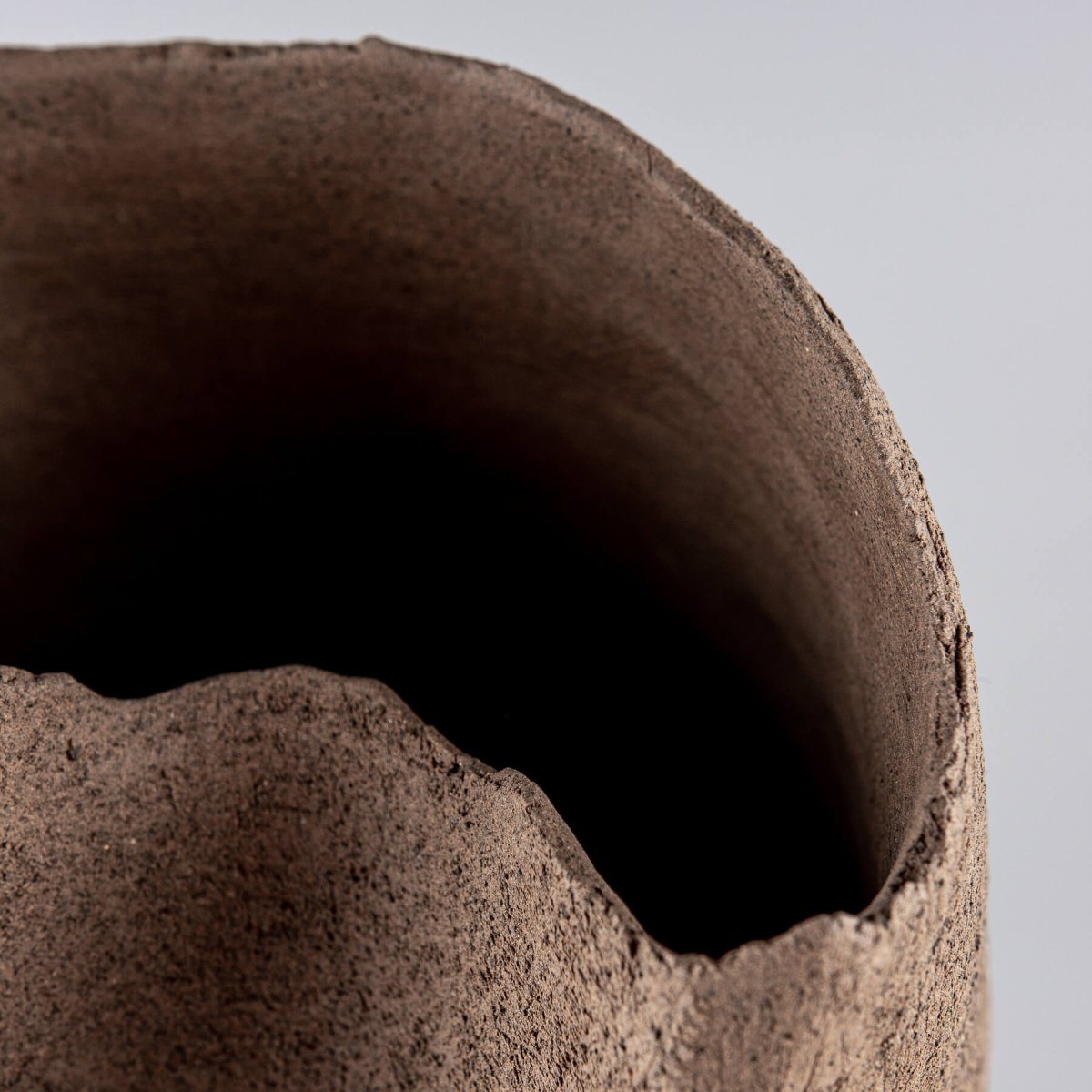 Artisan stoneware vase with a unique sculptural opening for fine dining restaurant display.