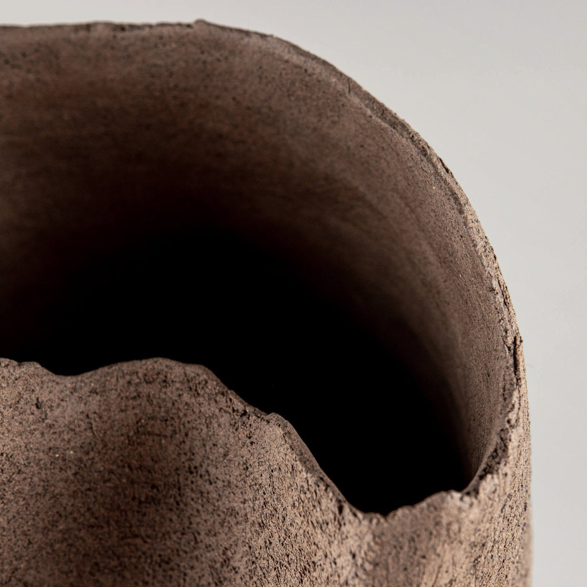 Artisan stoneware vase with a unique sculptural opening for fine dining restaurant display.