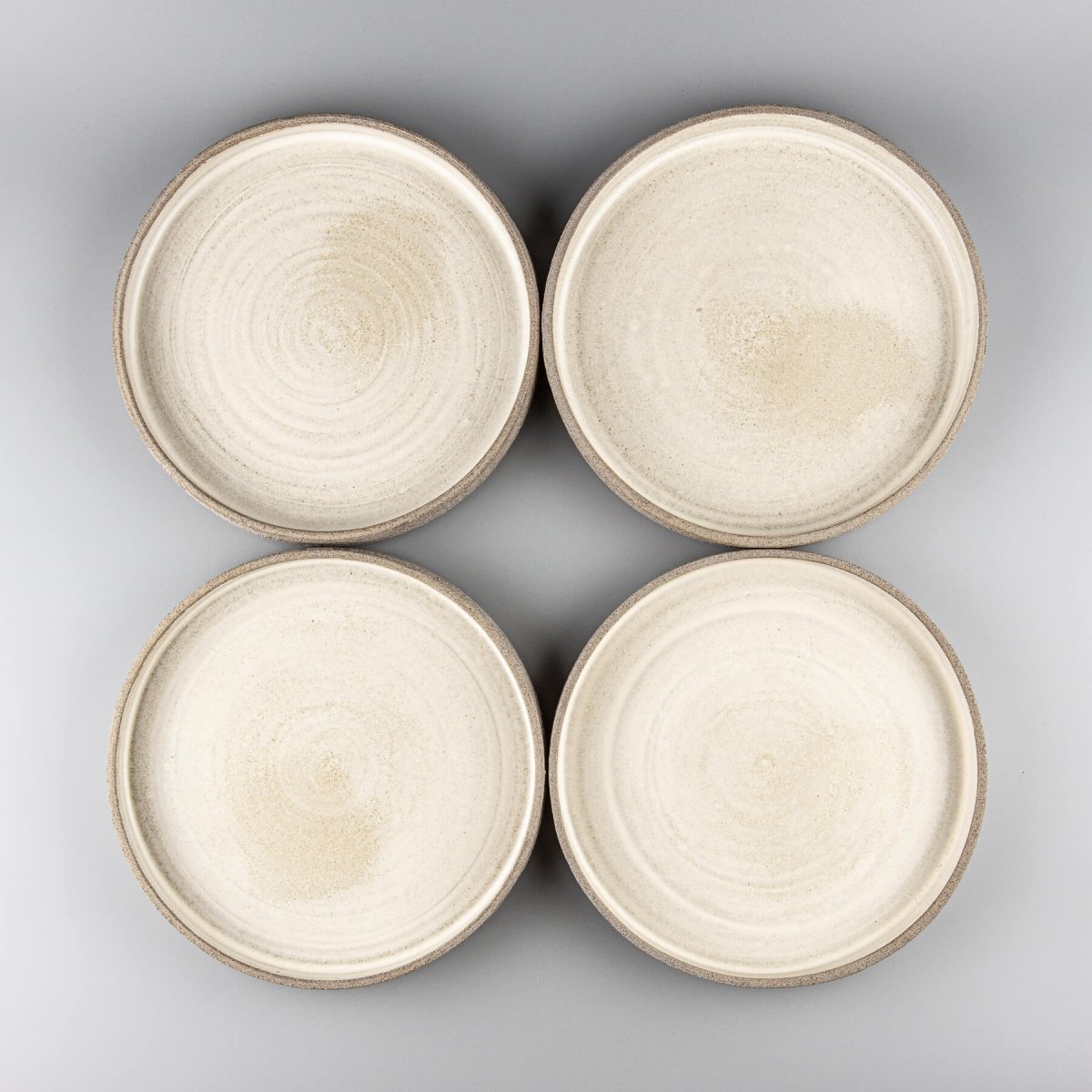 Set of handmade stoneware plates with matte white glaze and textured sides.