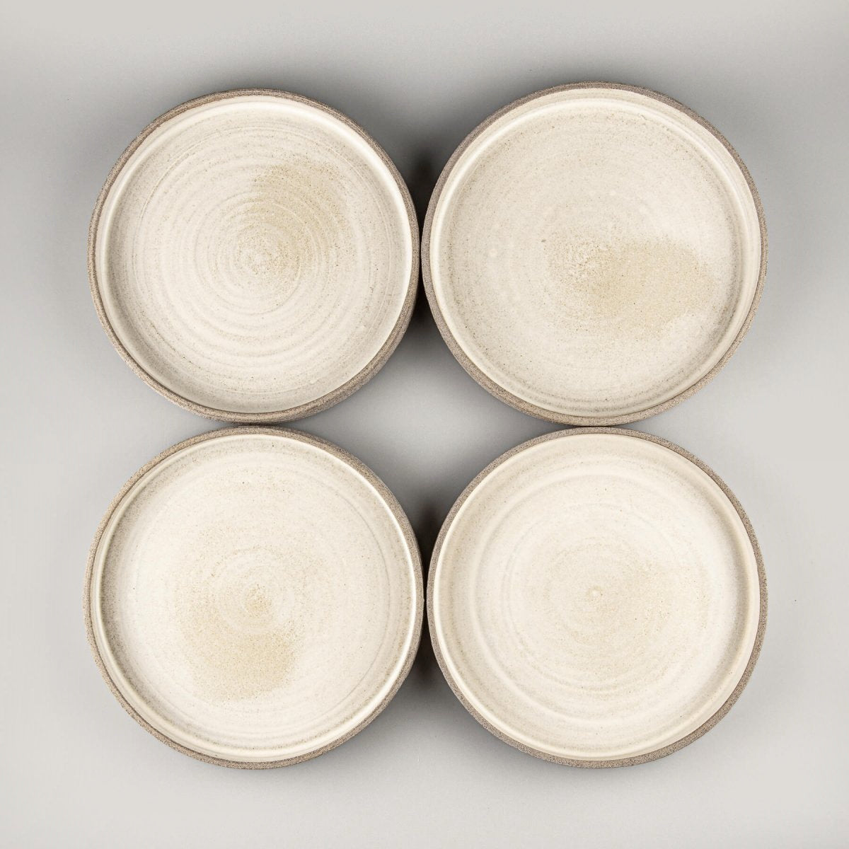 Set of handmade stoneware plates with matte white glaze and textured sides.