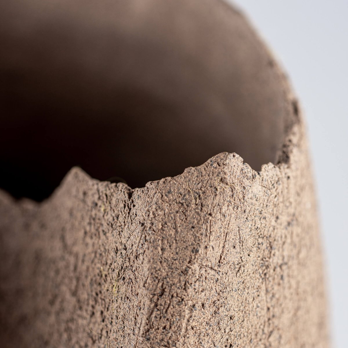 Textured edge of handmade stoneware vase with organic unglazed finish for boutique hotel and fine dining interiors.