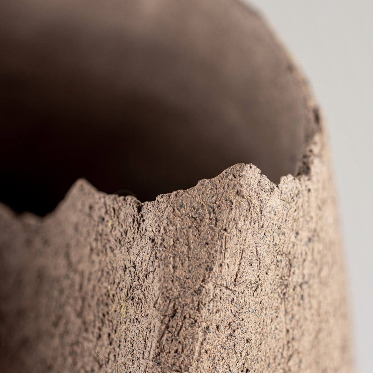 Textured edge of handmade stoneware vase with organic unglazed finish for boutique hotel and fine dining interiors.
