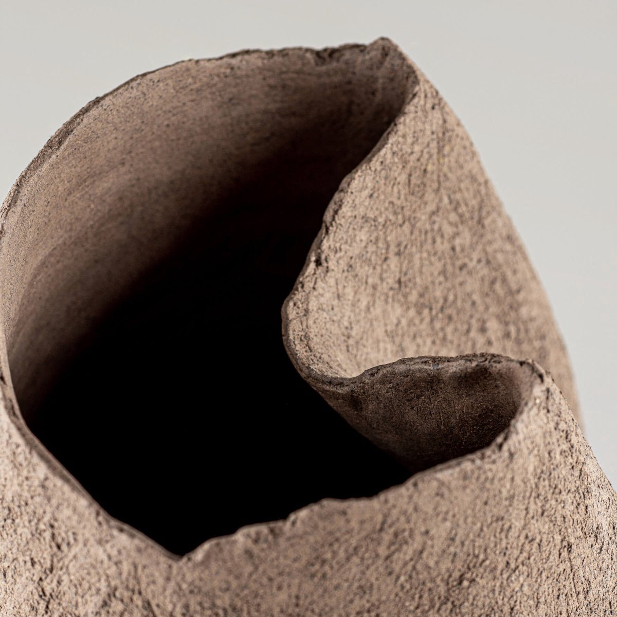 Decorative brown stoneware vase featuring a textured, unglazed surface for interior design.