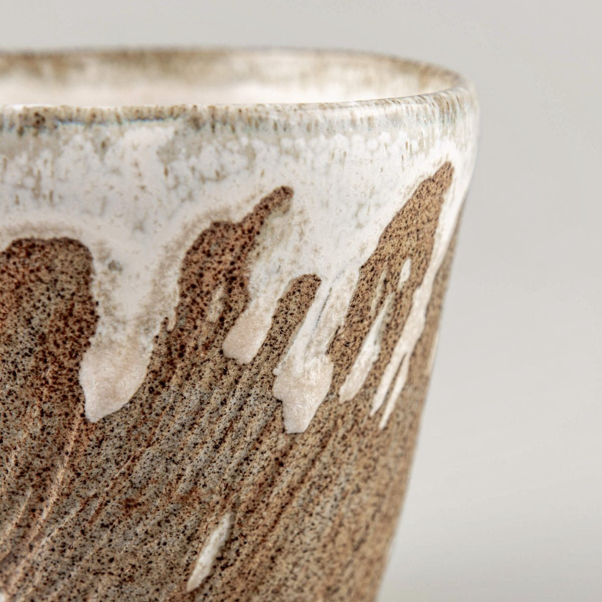 Detailed side of ceramic espresso mug with flowing glaze over textured clay.