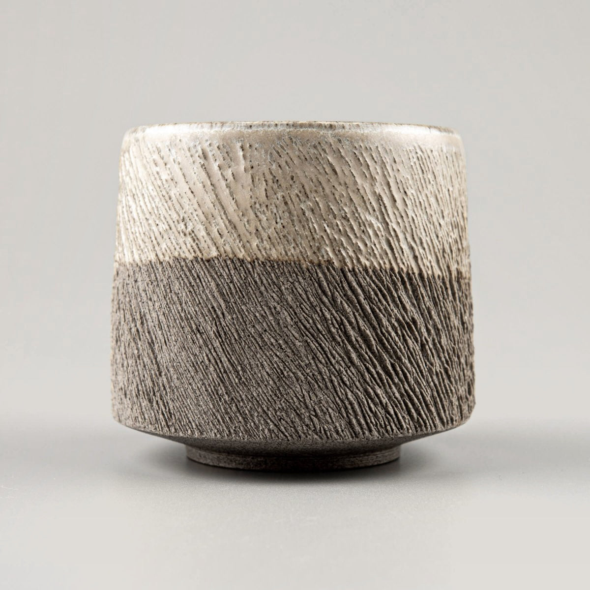 Detail of textured stoneware pottery coffee mug with partially glazed surface for modern design.