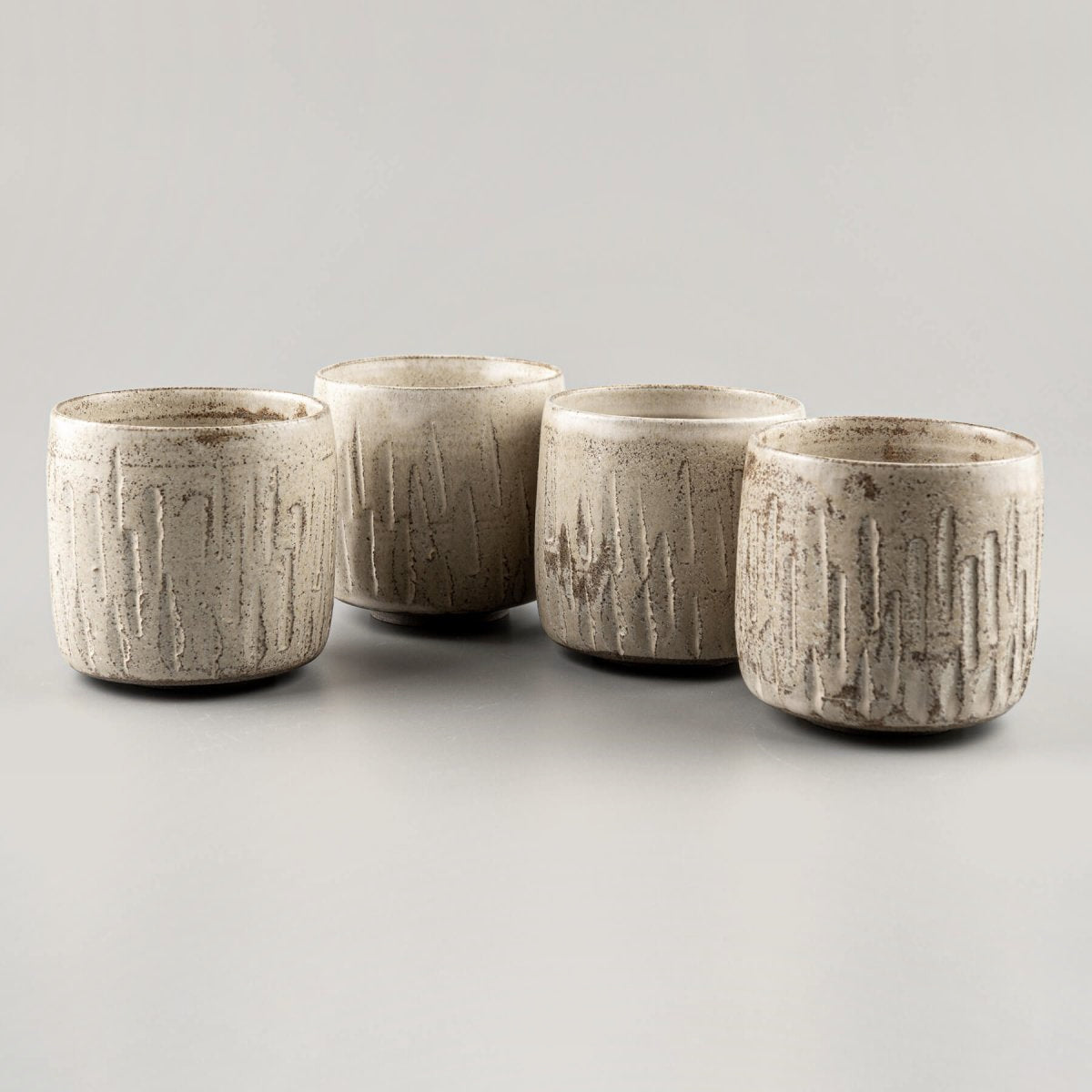 Ceramic handmade cups set with carved stoneware texture and matte glaze finish.