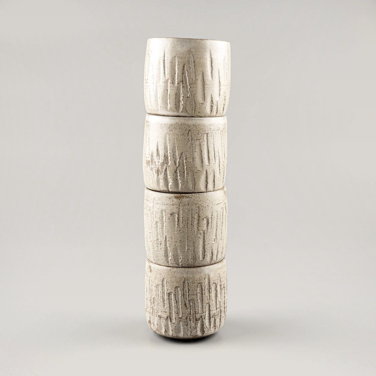 Stacked ceramic handmade cups with carved stoneware design and matte glaze.