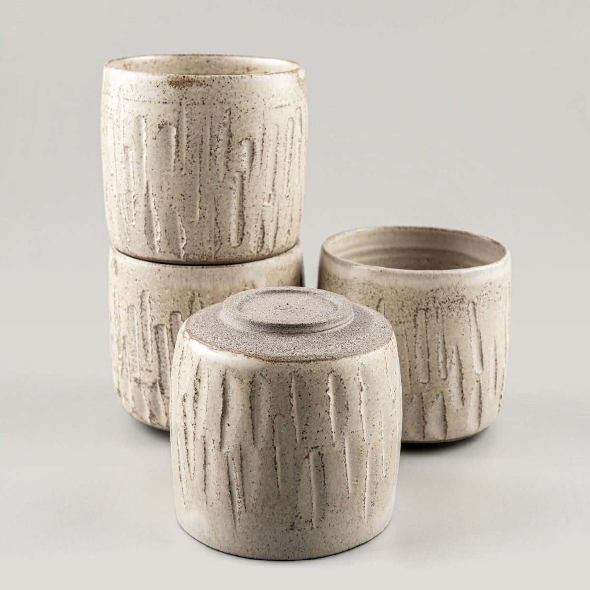 Stacked ceramic handmade cups with carved stoneware design and natural glaze.