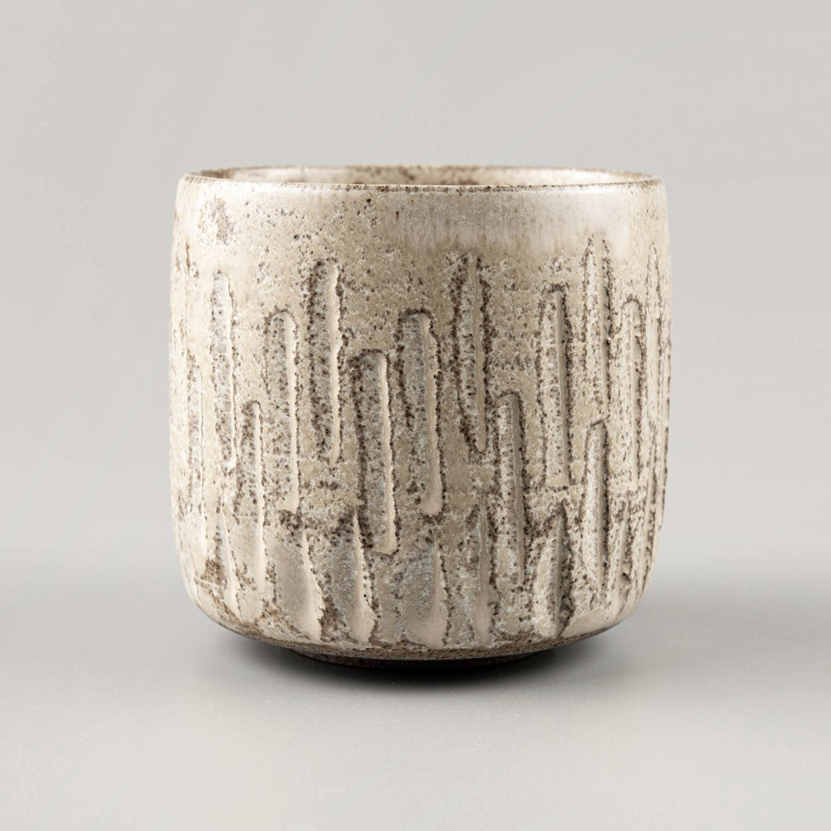 Detailed carving patterns on ceramic handmade cup with matte glaze.