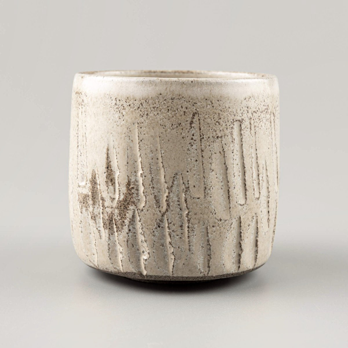 Artisan-crafted ceramic handmade cup with rustic carved stoneware texture.