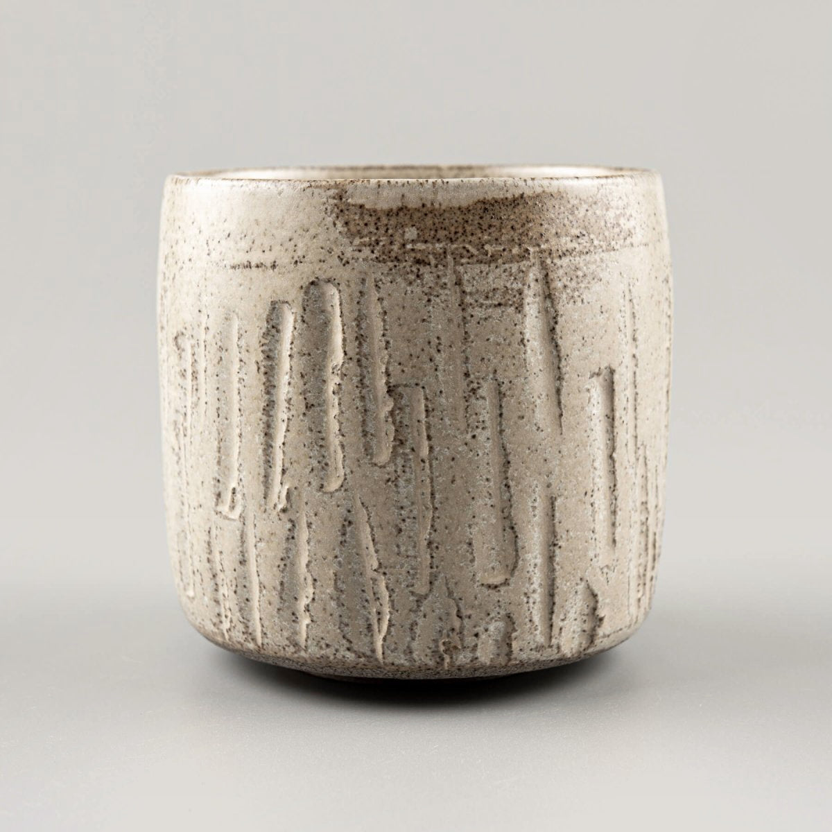Single ceramic handmade cup with textured carvings and rustic matte finish.