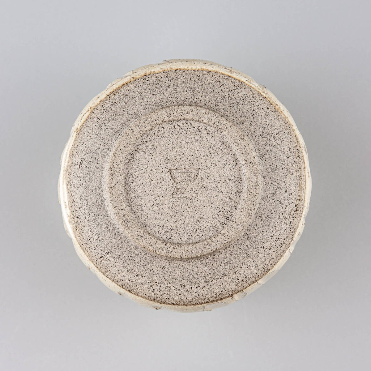 Bottom view of a handmade ceramic cup with a circular stoneware base design.