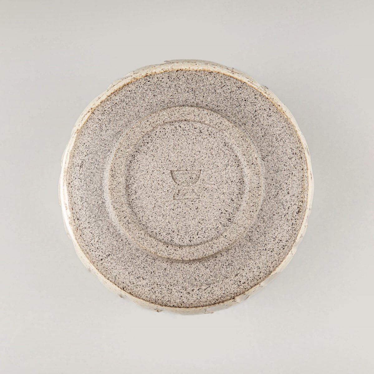 Bottom view of a handmade ceramic cup with a circular stoneware base design.