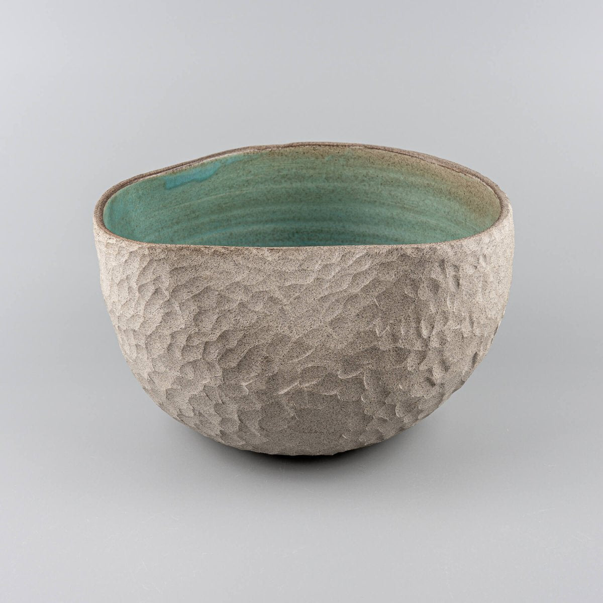 Collectible pottery vase with stoneware carvings and glazed turquoise interior for modern decor.