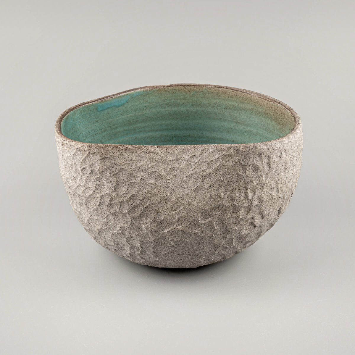 Collectible pottery vase with stoneware carvings and glazed turquoise interior for modern decor.