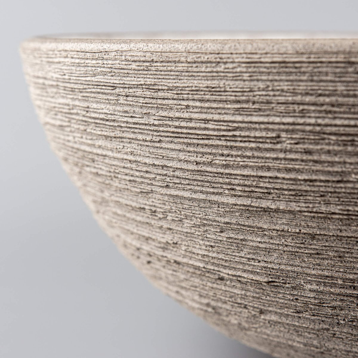 Decorative ceramic bowl angled to highlight the contrast between unglazed exterior and smooth glazed interior.