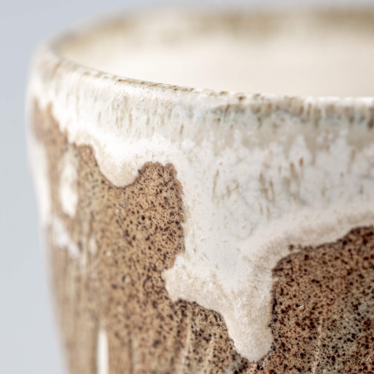 Close-up of rim on ceramic espresso mug with contrast between glaze and raw clay.