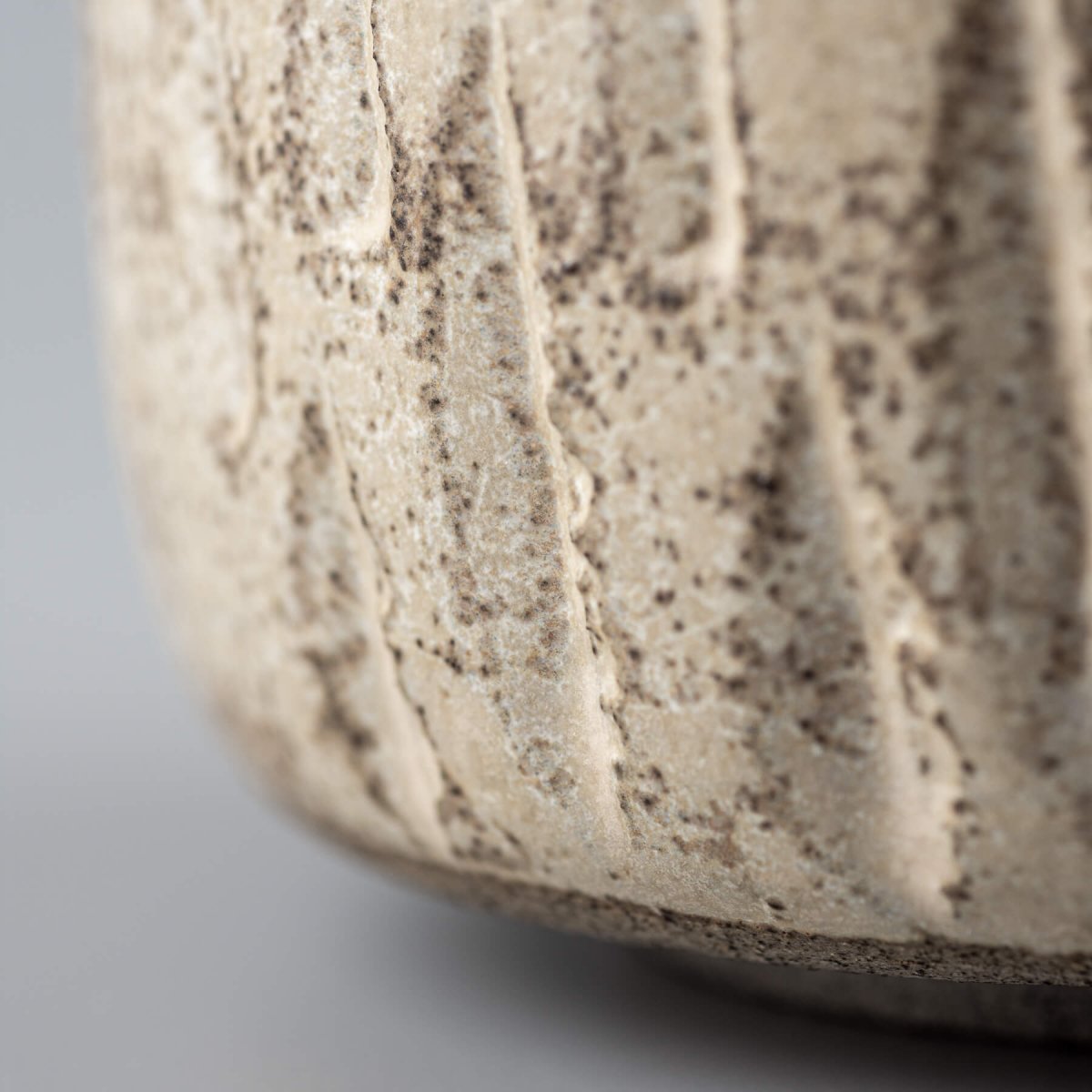 Close-up of ceramic handmade cup with carved surface and rustic matte finish.