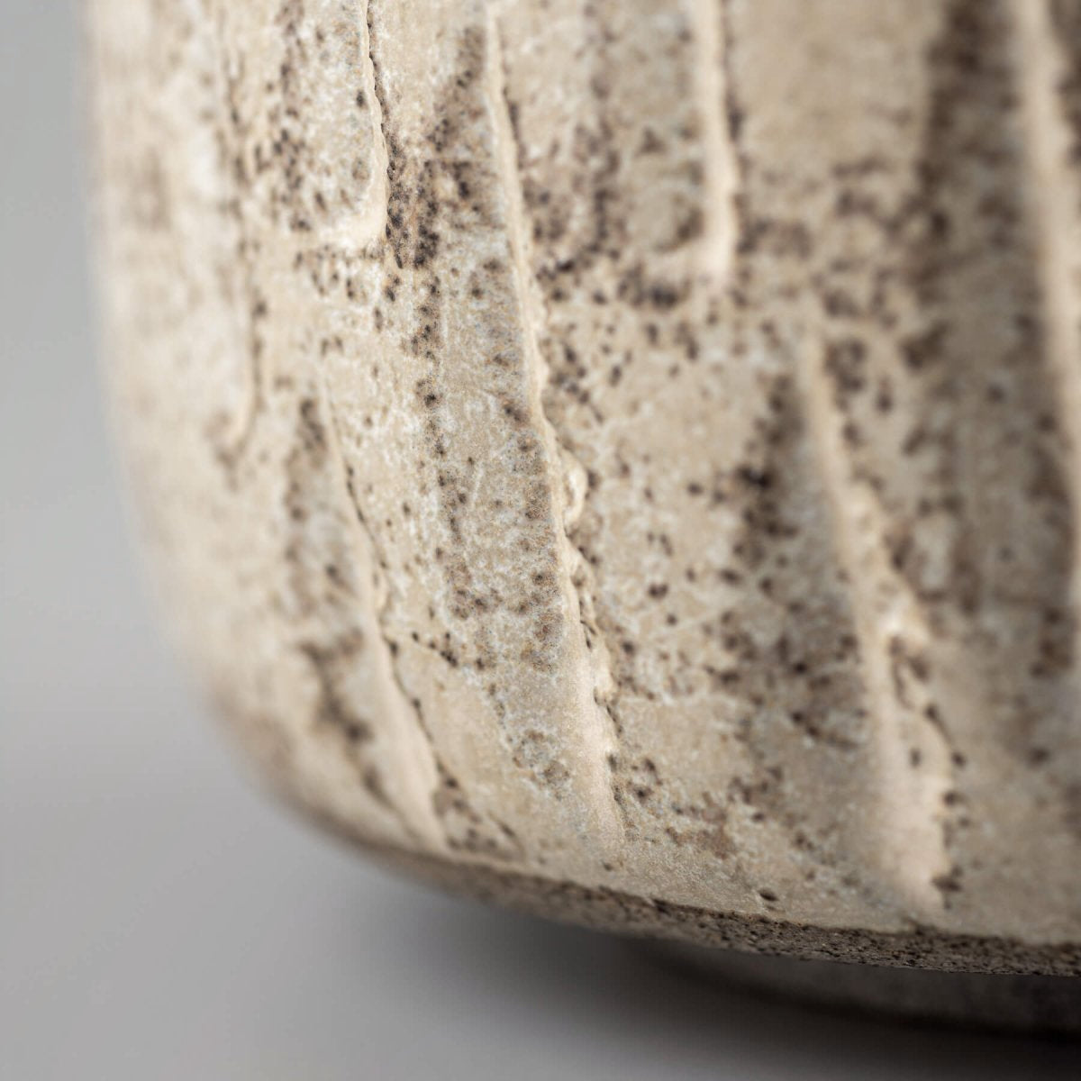 Close-up of ceramic handmade cup with carved surface and rustic matte finish.