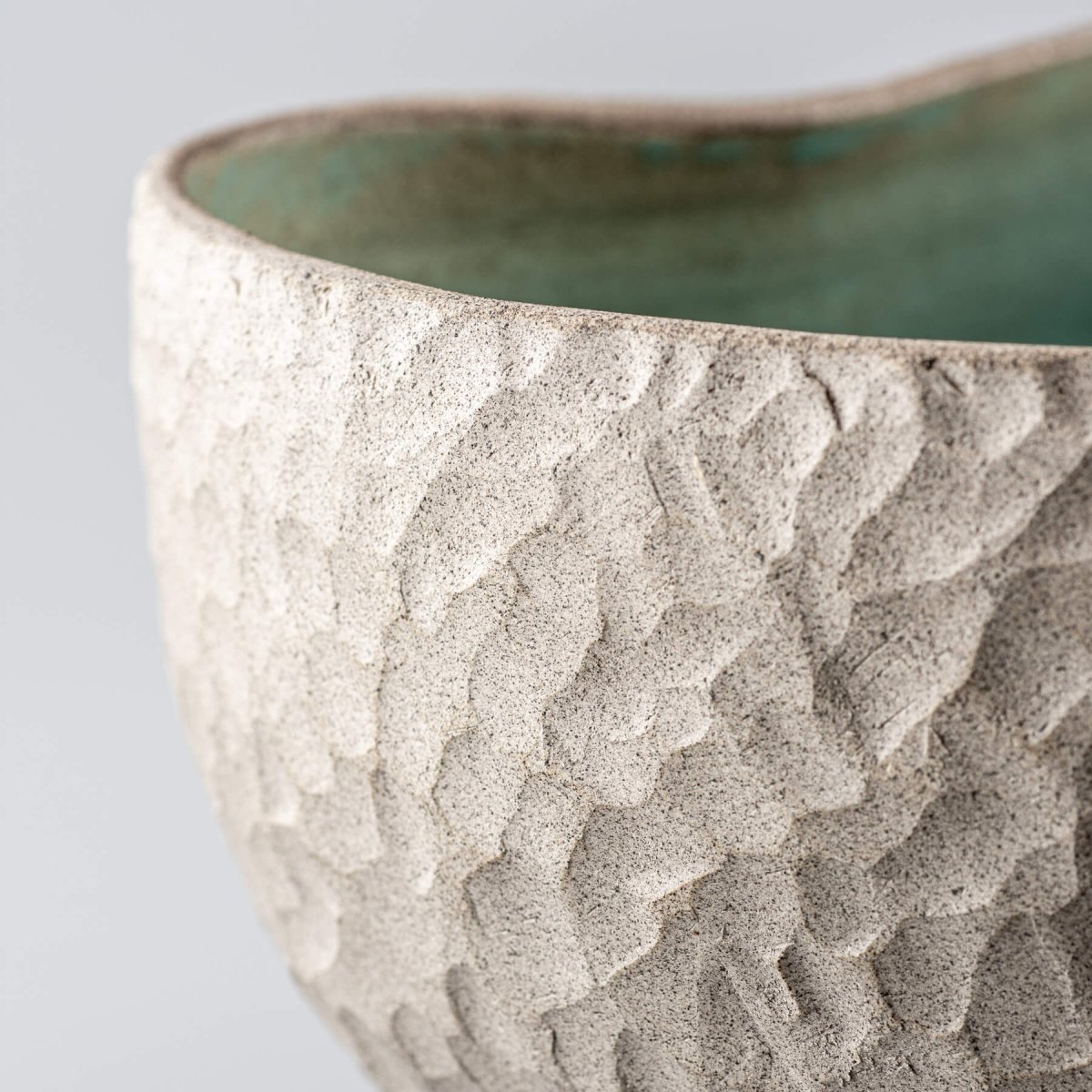 Handmade ceramic vases featuring a carved stoneware texture and a turquoise-glazed interior, suitable for decorative use.