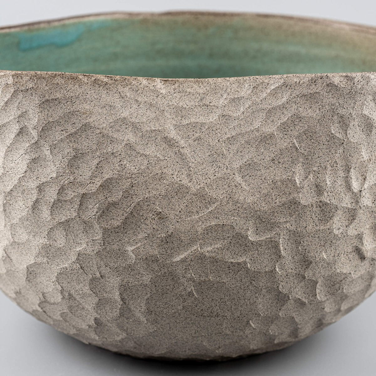 Rustic stoneware vase featuring a handmade, carved texture and decorative turquoise glaze for interior design.