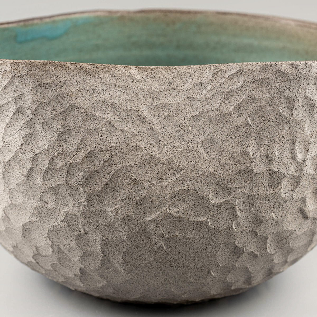 Rustic stoneware vase featuring a handmade, carved texture and decorative turquoise glaze for interior design.
