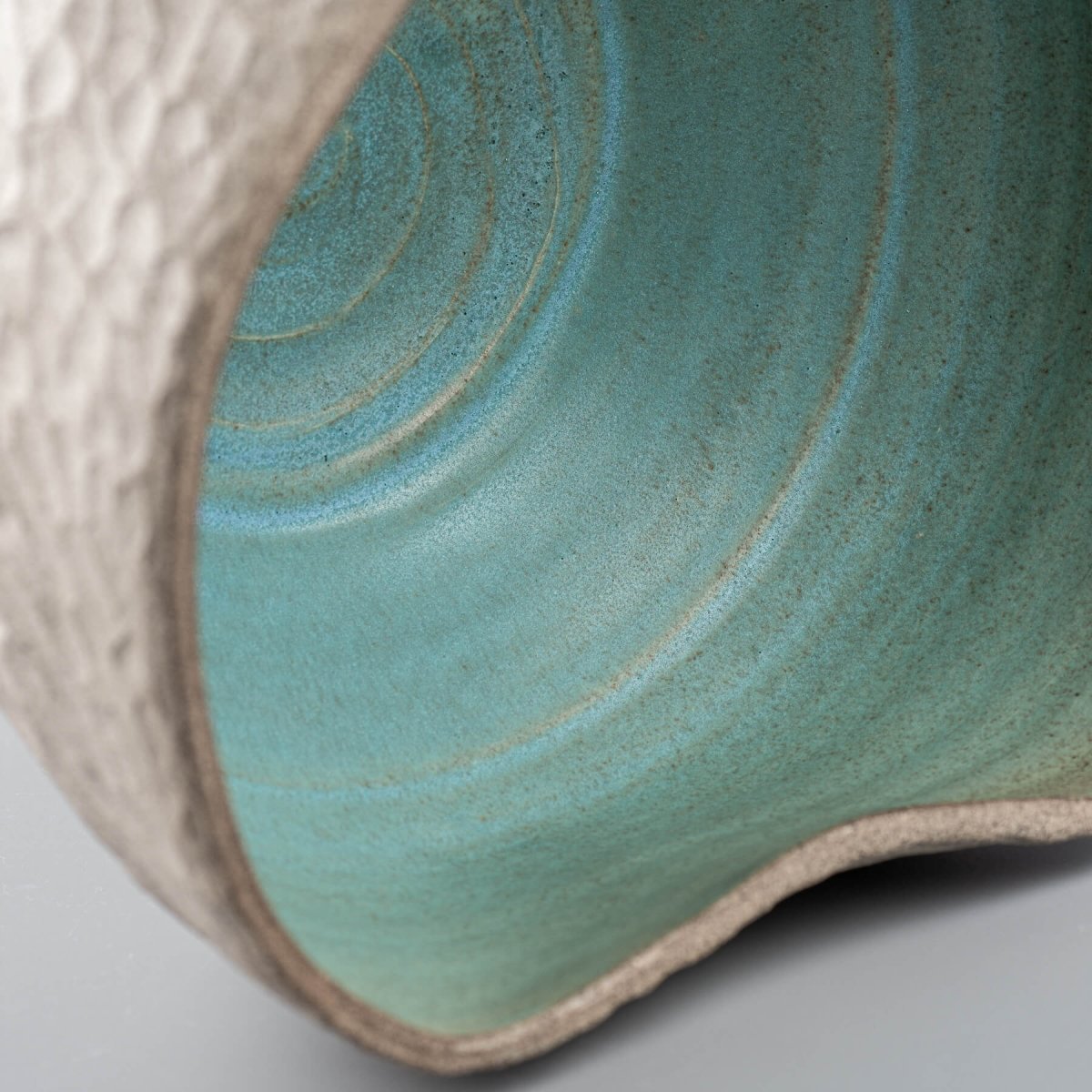 Close-up of turquoise-glazed interior of handmade ceramic vase for boutique hotel and home decor.