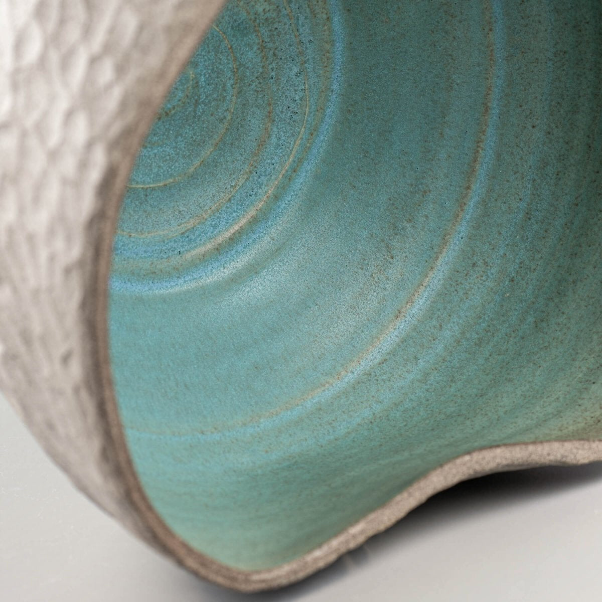 Close-up of turquoise-glazed interior of handmade ceramic vase for boutique hotel and home decor.