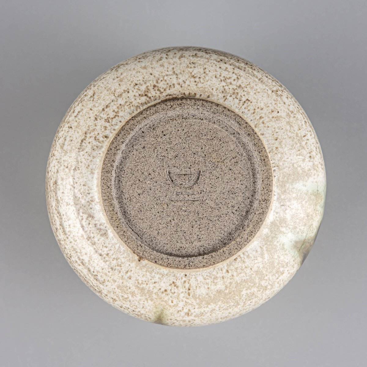 Handmade stoneware mug base showing artisan craftsmanship and natural clay texture.