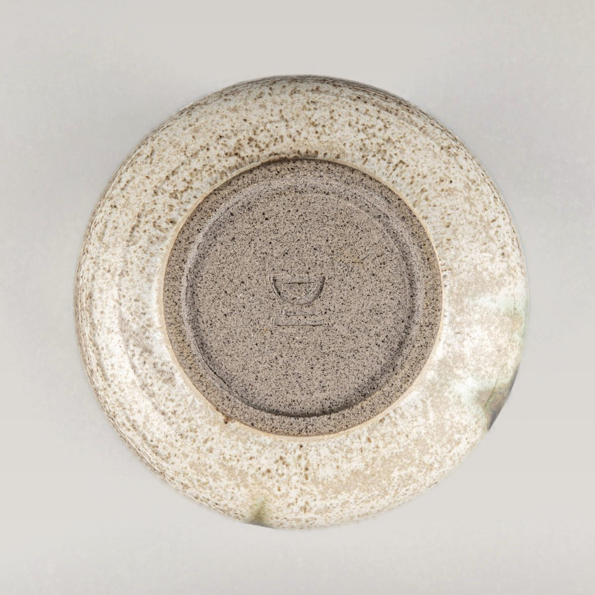 Handmade stoneware mug base showing artisan craftsmanship and natural clay texture.