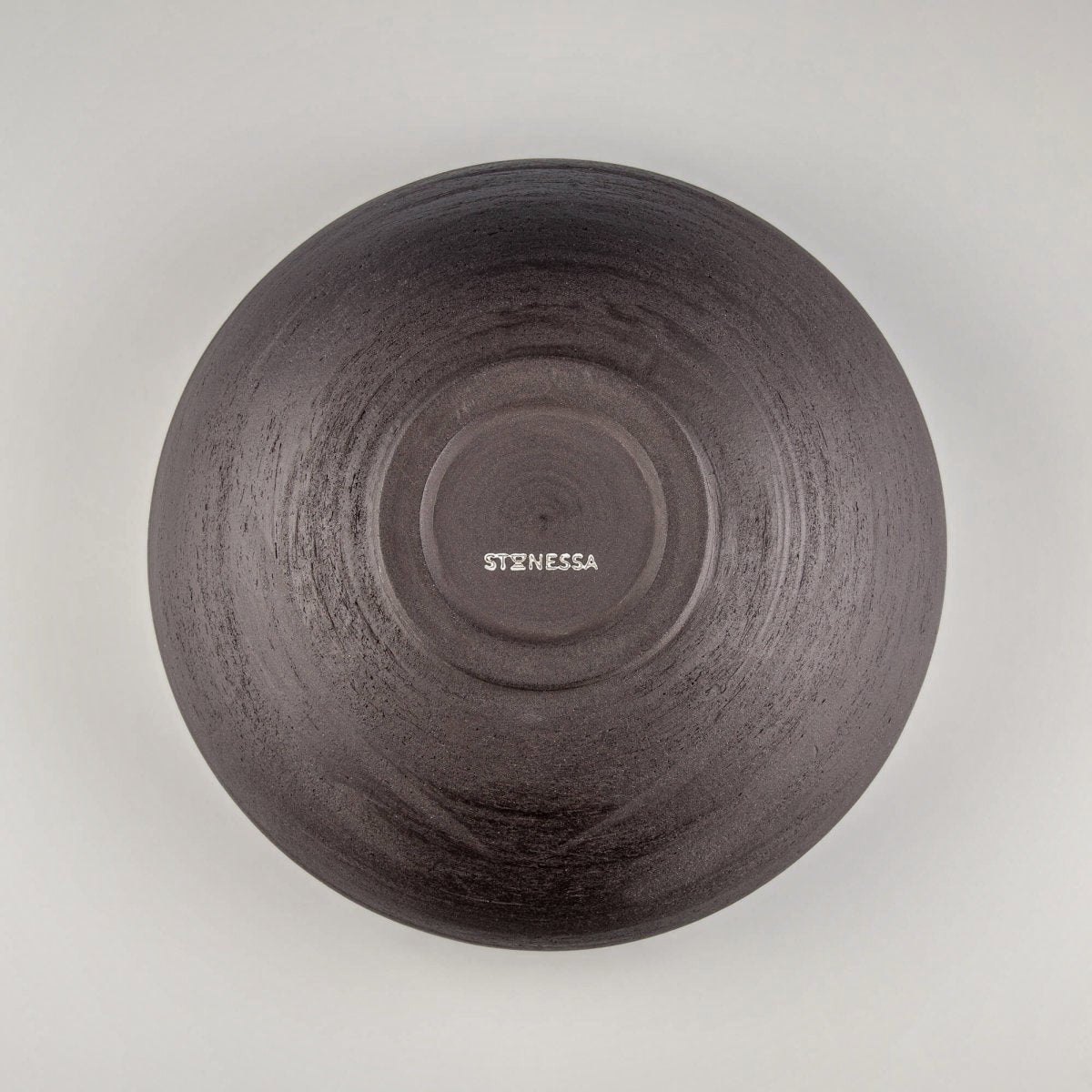 Interior detail of handmade serving bowl with circular wheel marks, speckled glaze, and ceramic fruit bowl style.