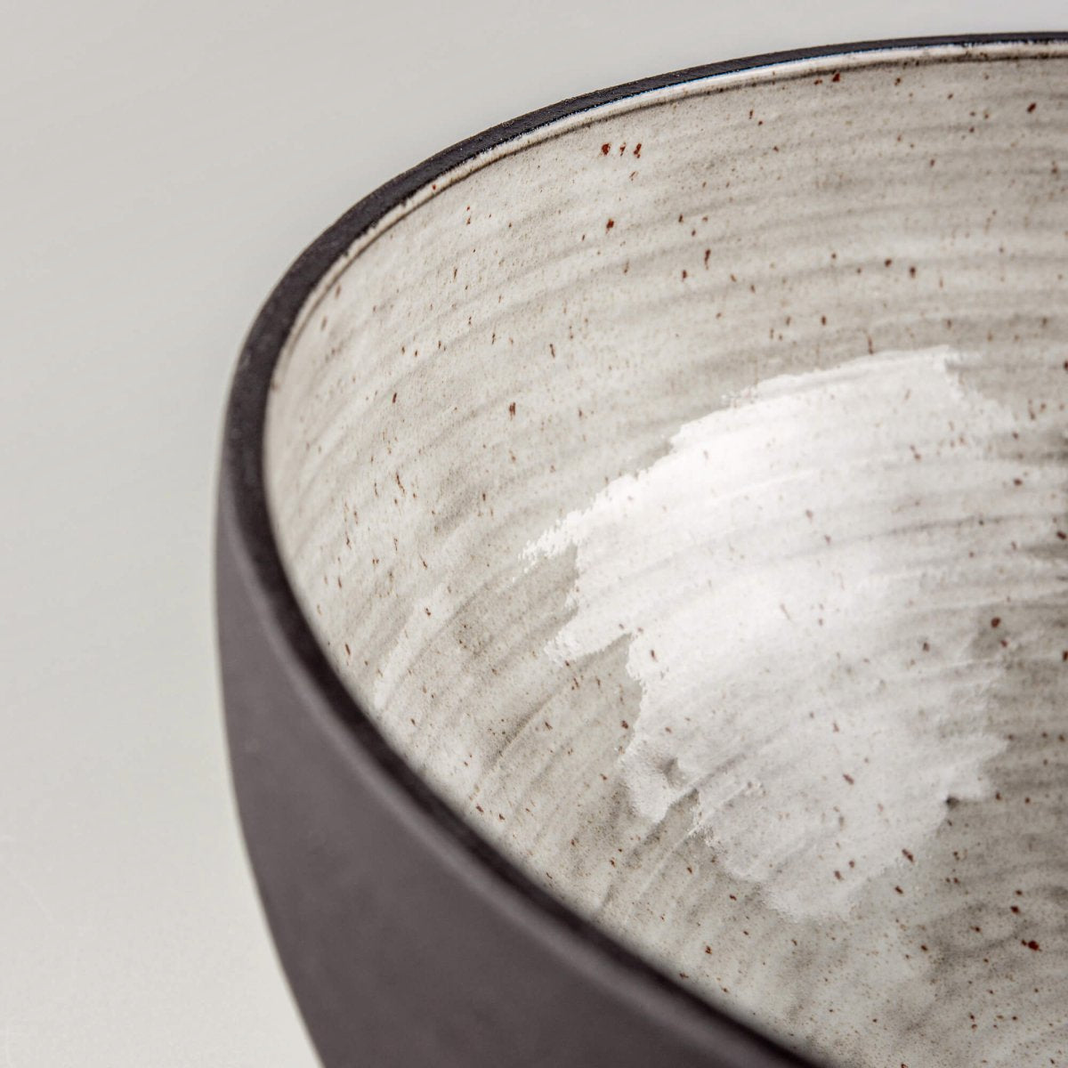 Bottom view of handmade serving bowl with dark textured ceramic exterior and stable footed base.