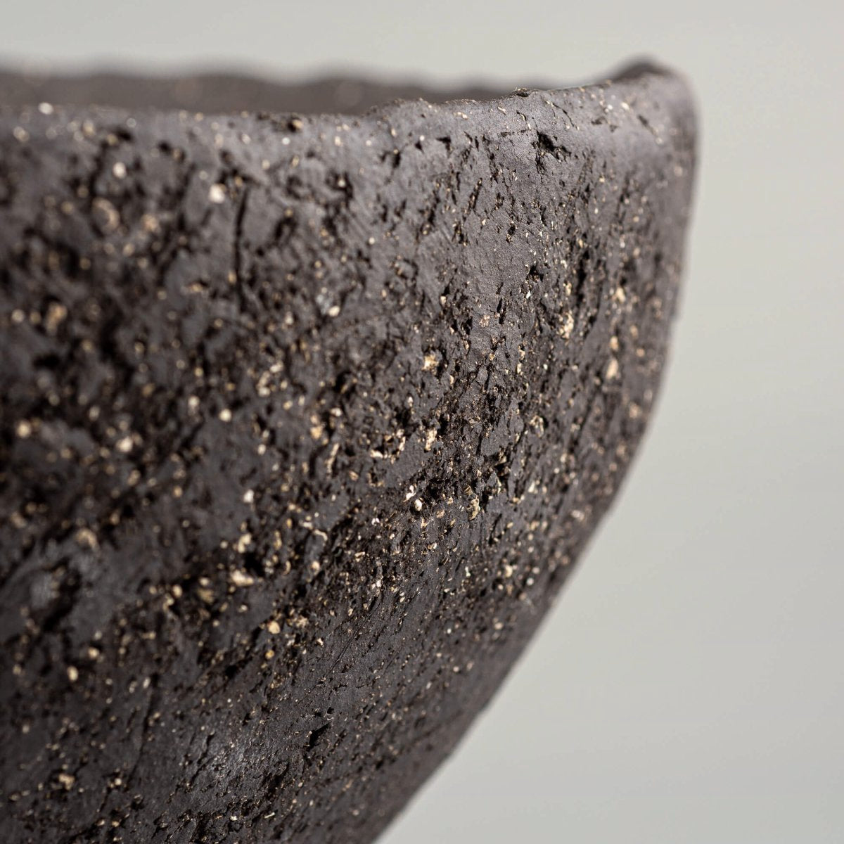 Handcrafted centerpiece edge close-up with dark textured ceramic finish for luxury homes and fine dining spaces.