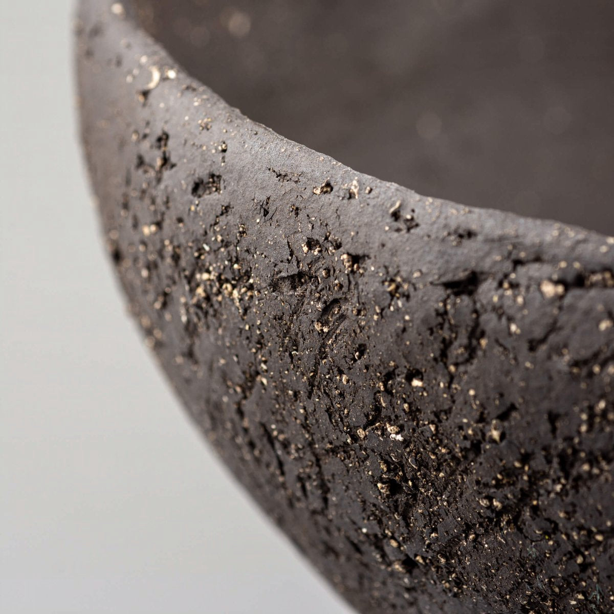 Handcrafted centerpiece rim detail with dark stoneware texture for boutique hotel and restaurant interiors.