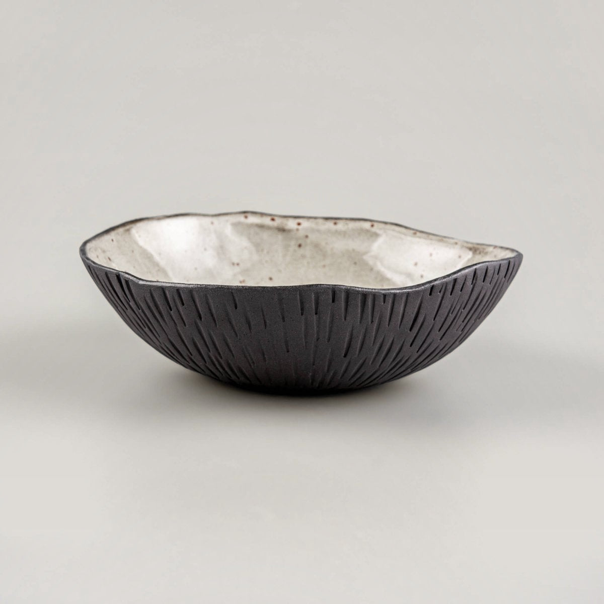 Handmade ceramic bowl with textured exterior and speckled glaze, designed for fine dining and luxury restaurant tableware.