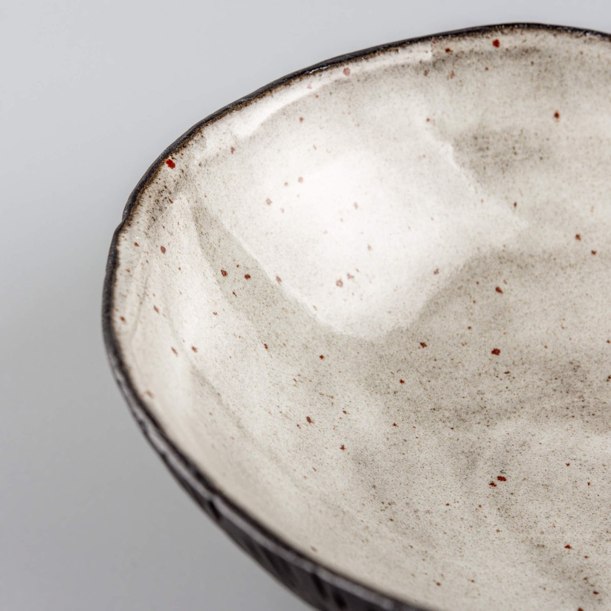 Close-up of a handmade ceramic bowl interior showing smooth glaze and subtle speckling for refined food presentation.