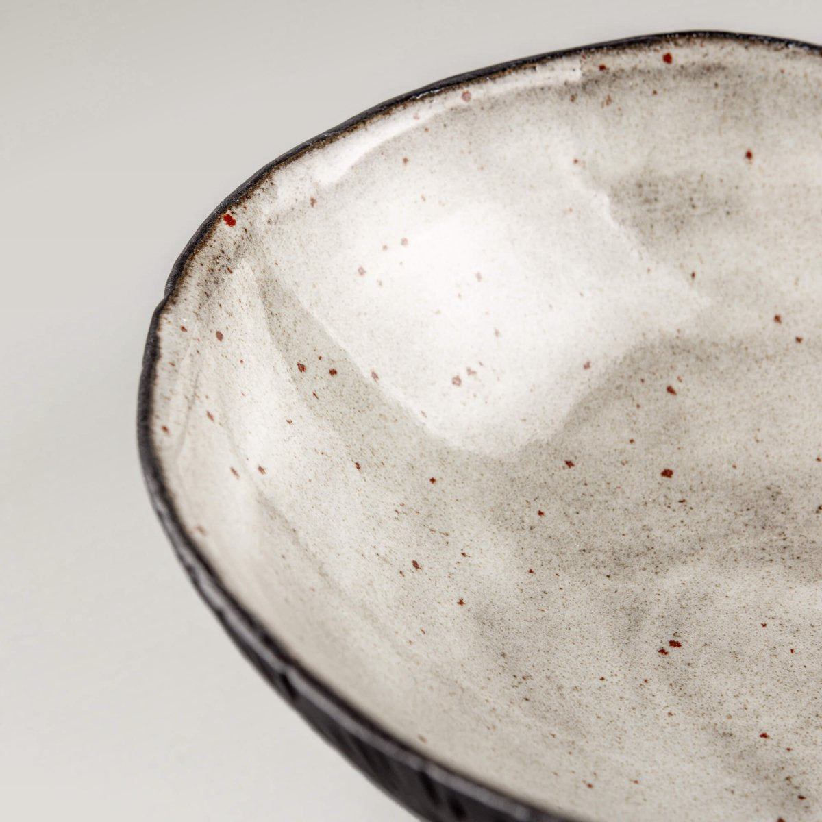 Close-up of a handmade ceramic bowl interior showing smooth glaze and subtle speckling for refined food presentation.