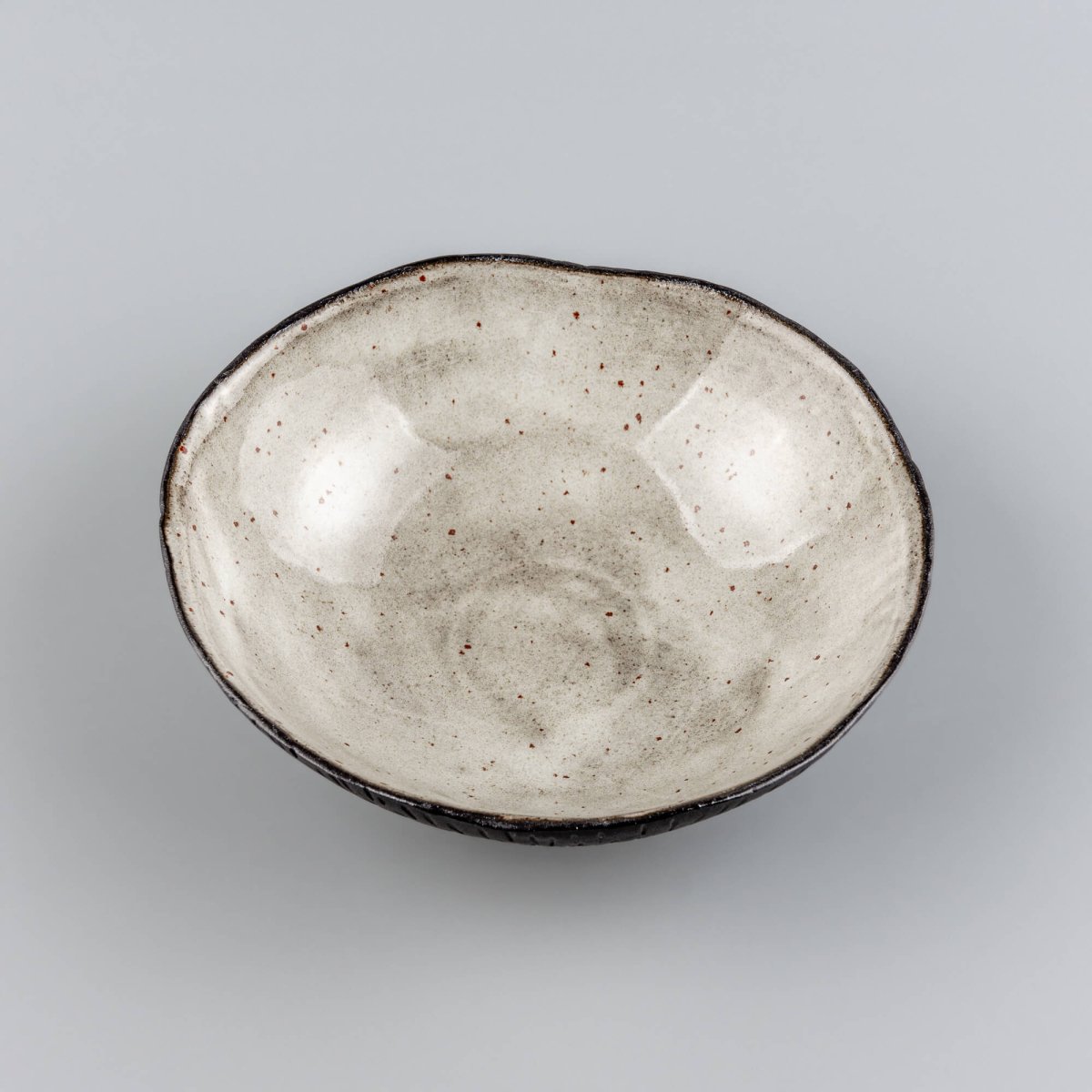 Top view of a handmade ceramic bowl with a natural speckled glaze, ideal for fine-dining restaurants and modern tableware.
