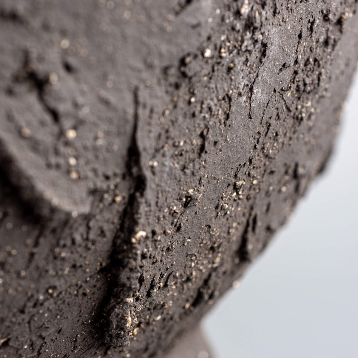 Handmade decorative bowl rim close-up with dark stoneware texture, organic edge, and handmade decor character.