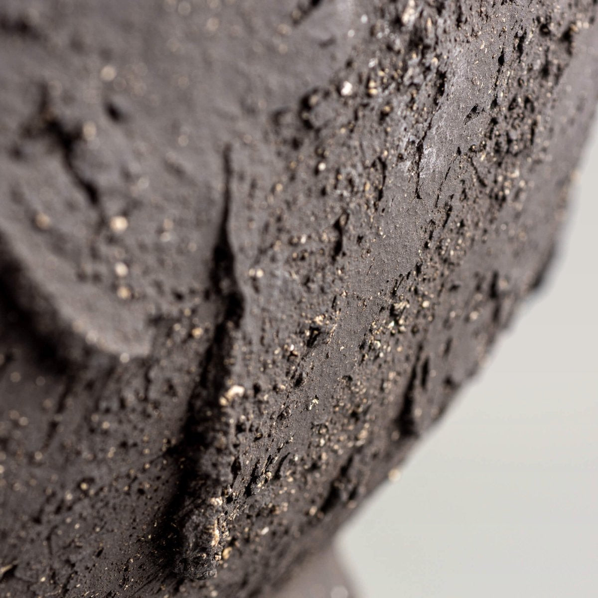 Handmade decorative bowl rim close-up with dark stoneware texture, organic edge, and handmade decor character.